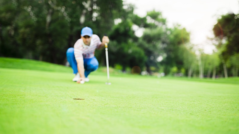 Golf player marking ball on the putting green before lifting the ball